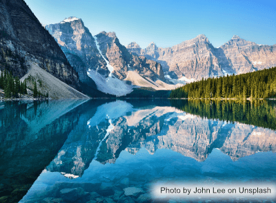 A photograph of a mountain range mirrored in a lake. Picture by John Lee on Unsplash.