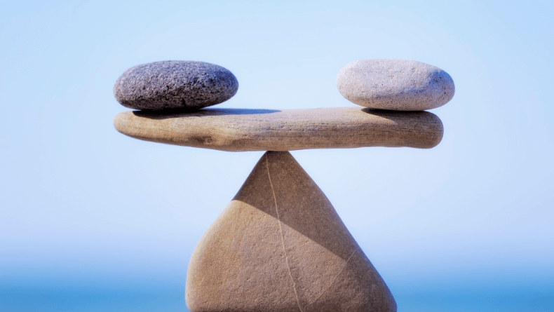 Two stones balance on top of a flat stone, which balances on the tip of a fourth stone. It's all about balance.