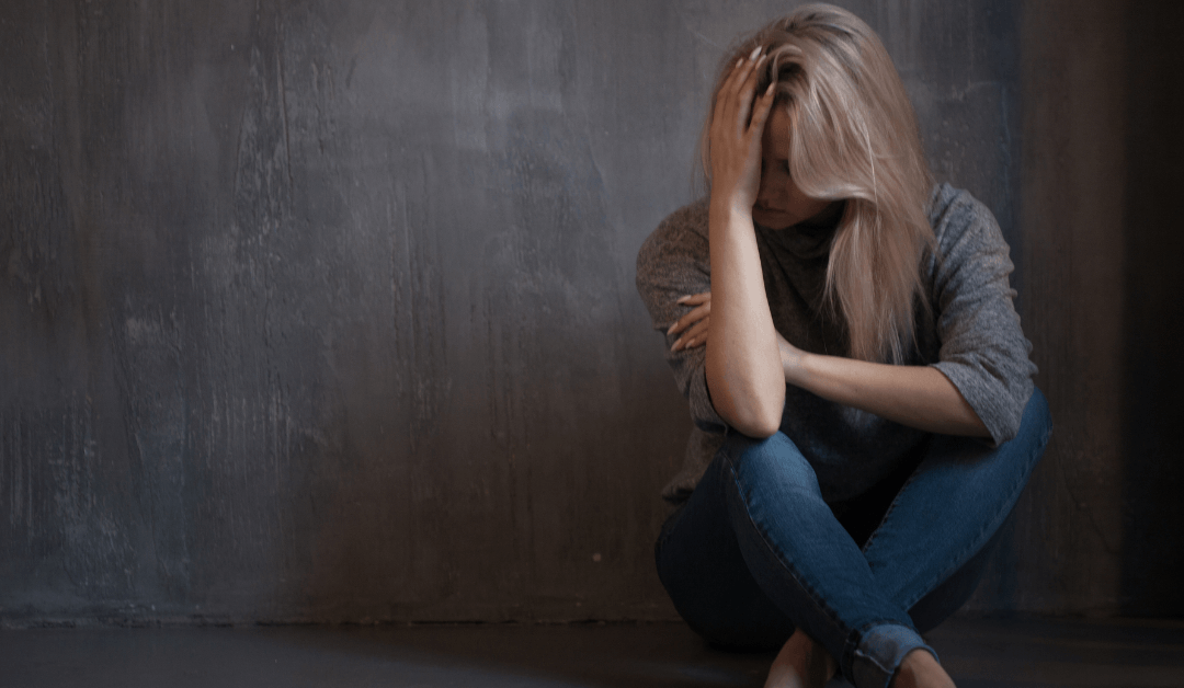 A woman hiding her face in her arms because she suffers from anxiety.