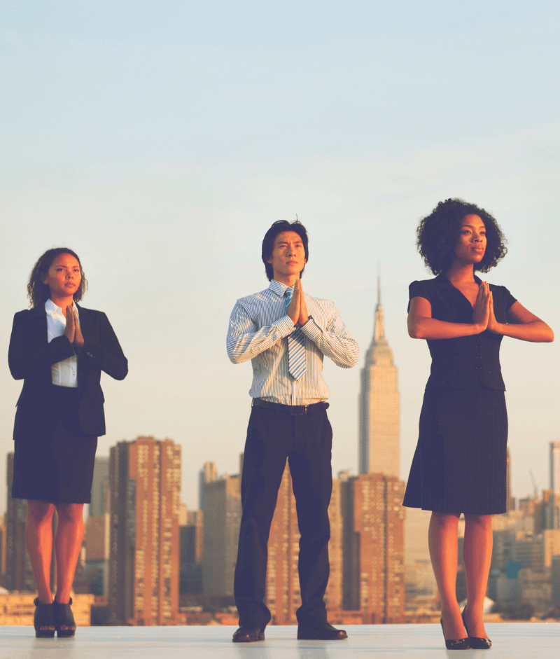 Two women and a man wearing business clothes meditate together.