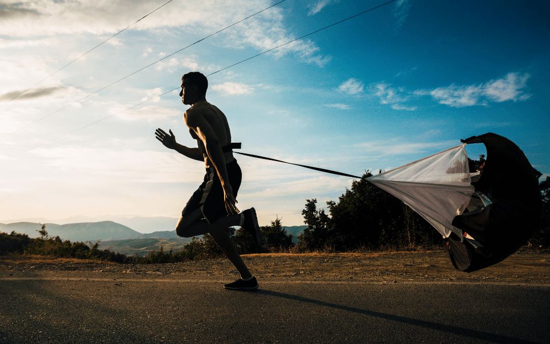 Man running but he is held back by a parachute.