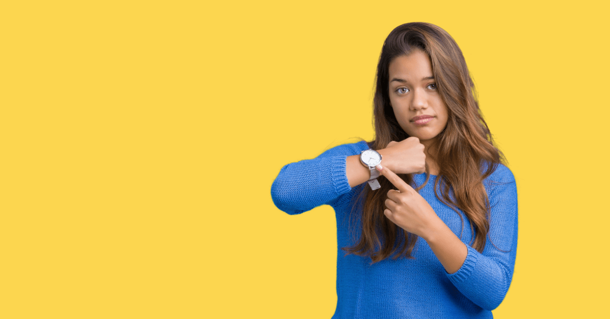 A woman taps her watch with impatience.